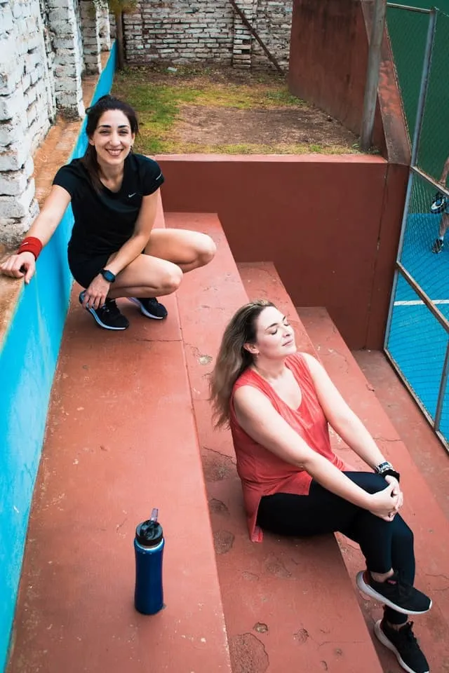 Deux femmes se reposant sur des escaliers après une séance de crossfit.