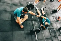 Deux crossfiteurs au sol, fatigués, se faisant un fist bump.