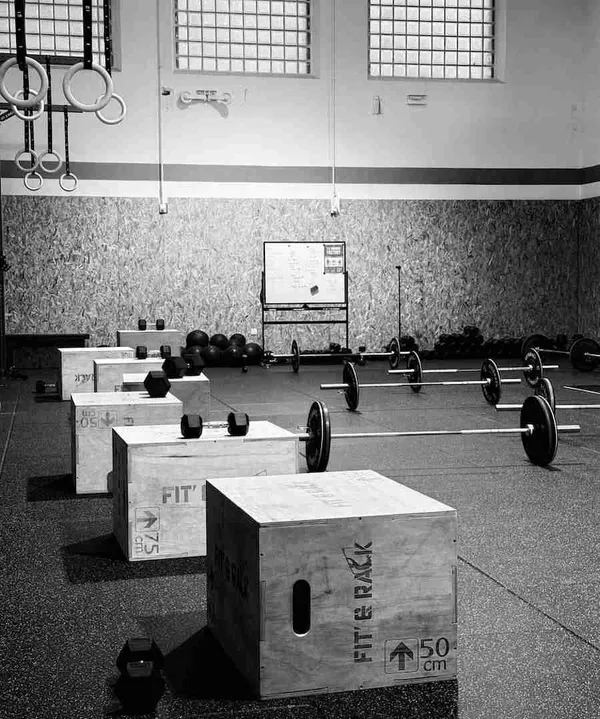 Vue d'ensemble de la box avec ses espaces, haltères et barres olympiques prêtes à l'emploi.